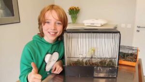 Wellensittich Krallenschneiden-Ein Junge mit Wellensittich im Käfig beim Tierarzt